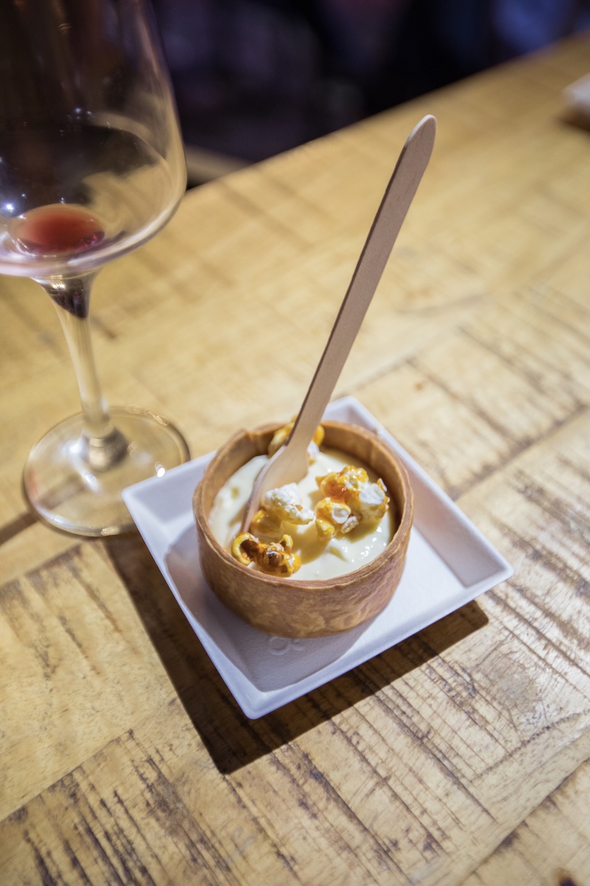 Bouchée sucrée servie dans une coupelle, à côté d'un verre de vin