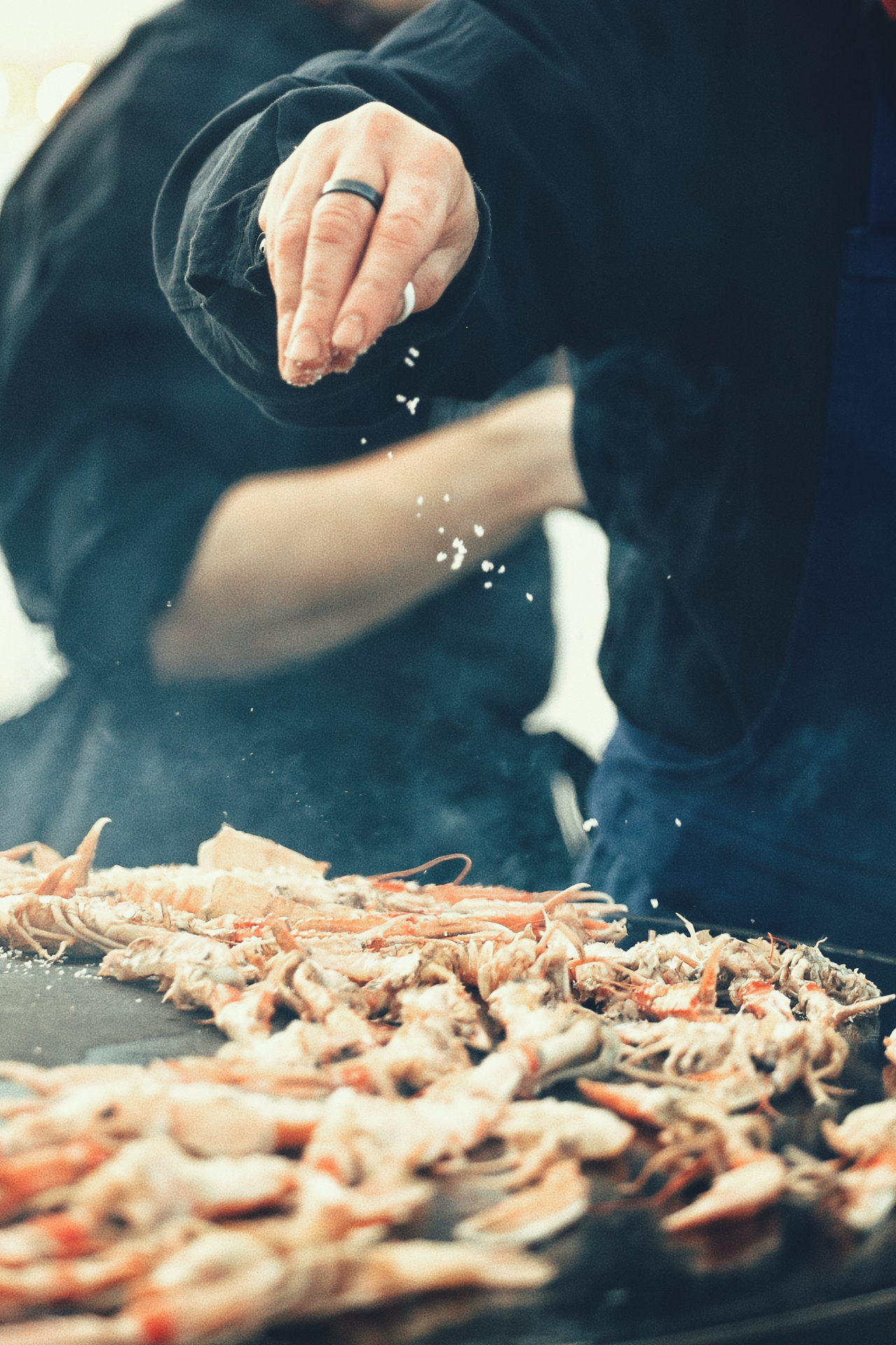 Chef en train de saler des langoustines sur une plancha