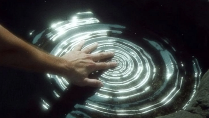 Main effleurant l'eau, créant des ondulations de lumière