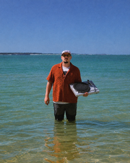 Segnor Capeo, Live DJ, debout dans l'eau avec ses platines face à la mer