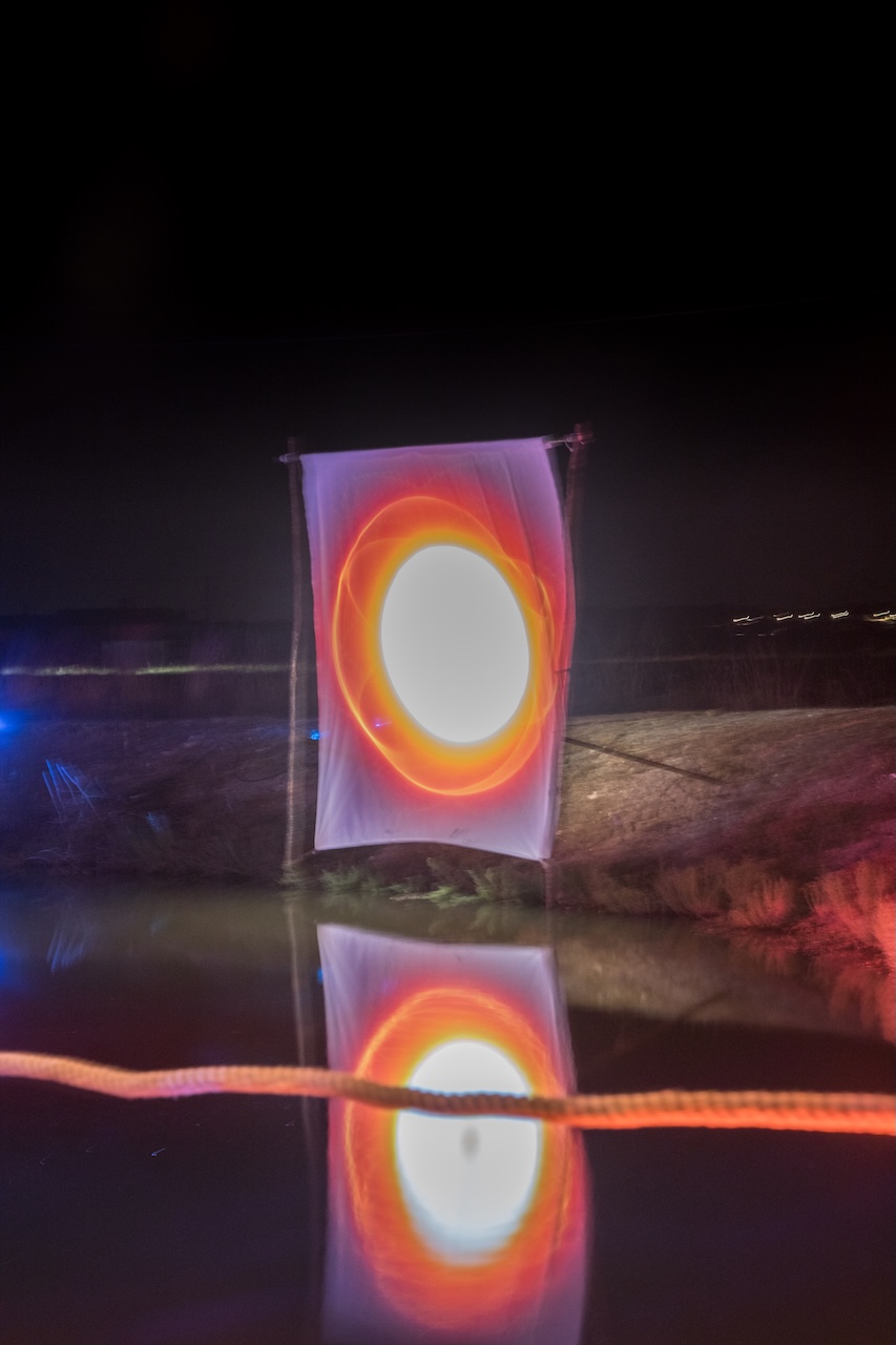 Installation lumineuse en forme de lune reflétée dans l'eau la nuit