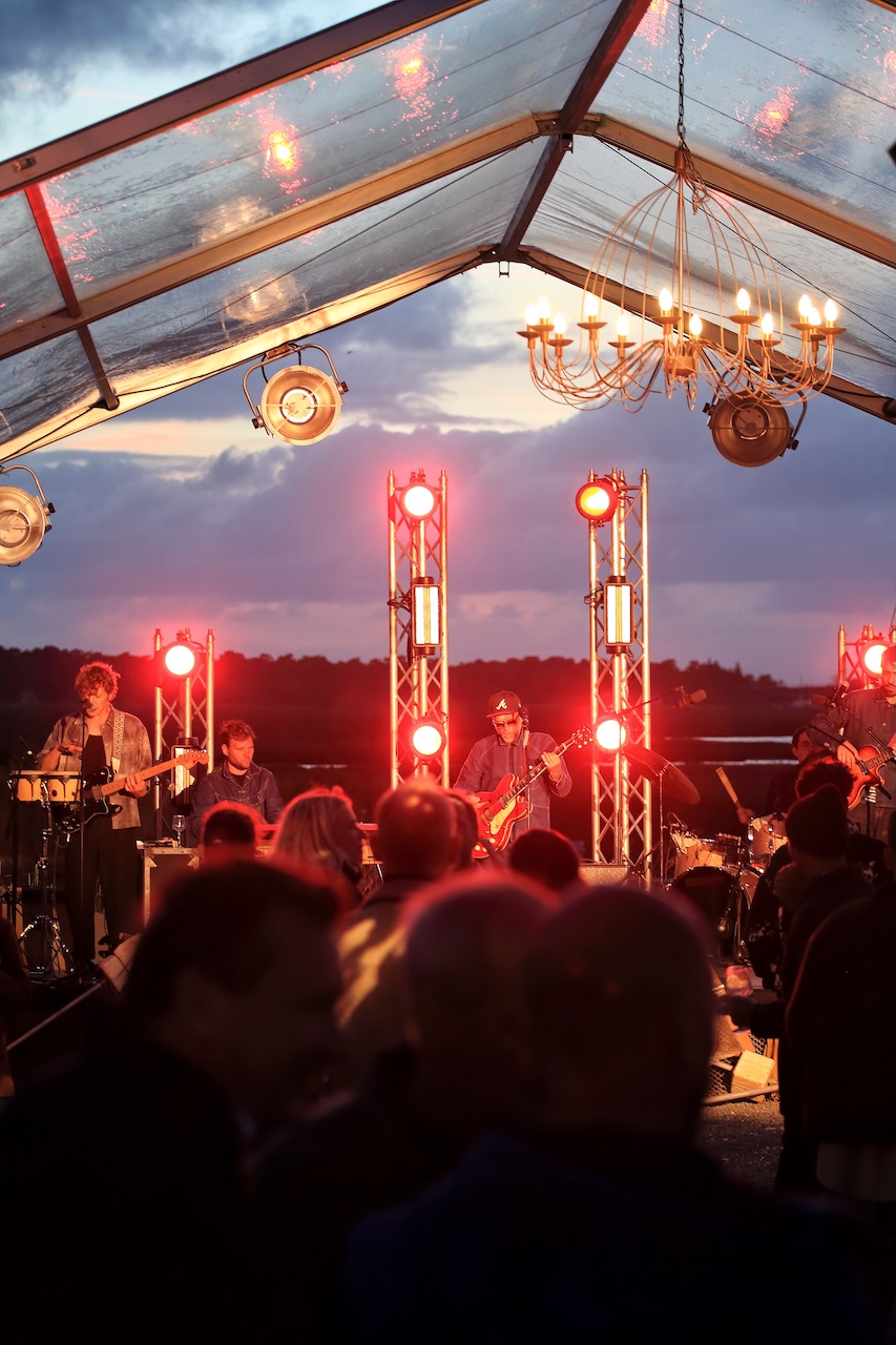 Groupe de musiciens sur scène sous les lustres et les lumières rouges