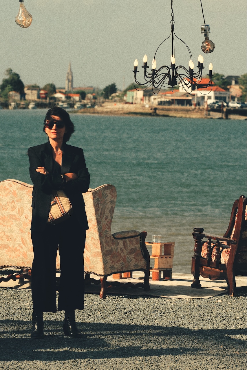 Femme debout devant la Seudre, entre fauteuils vintage et lustre suspendu