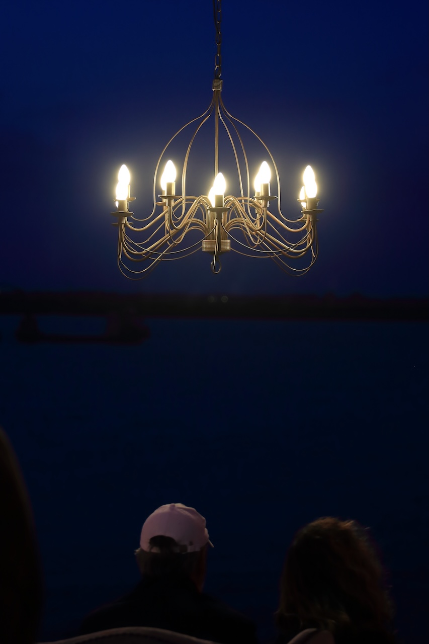 Lustre en fer forgé allumé au-dessus du public à la tombée de la nuit