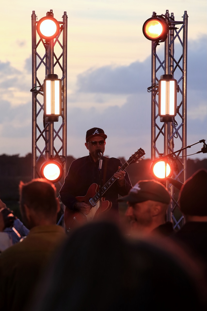 Guitariste chantant devant les projecteurs au coucher du soleil